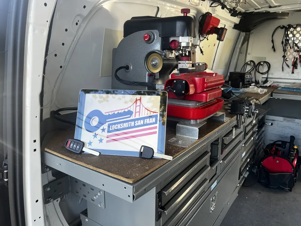 Inside the van: the key-cutting machine, the vice and the tool drawers, with the company sign on the bench.